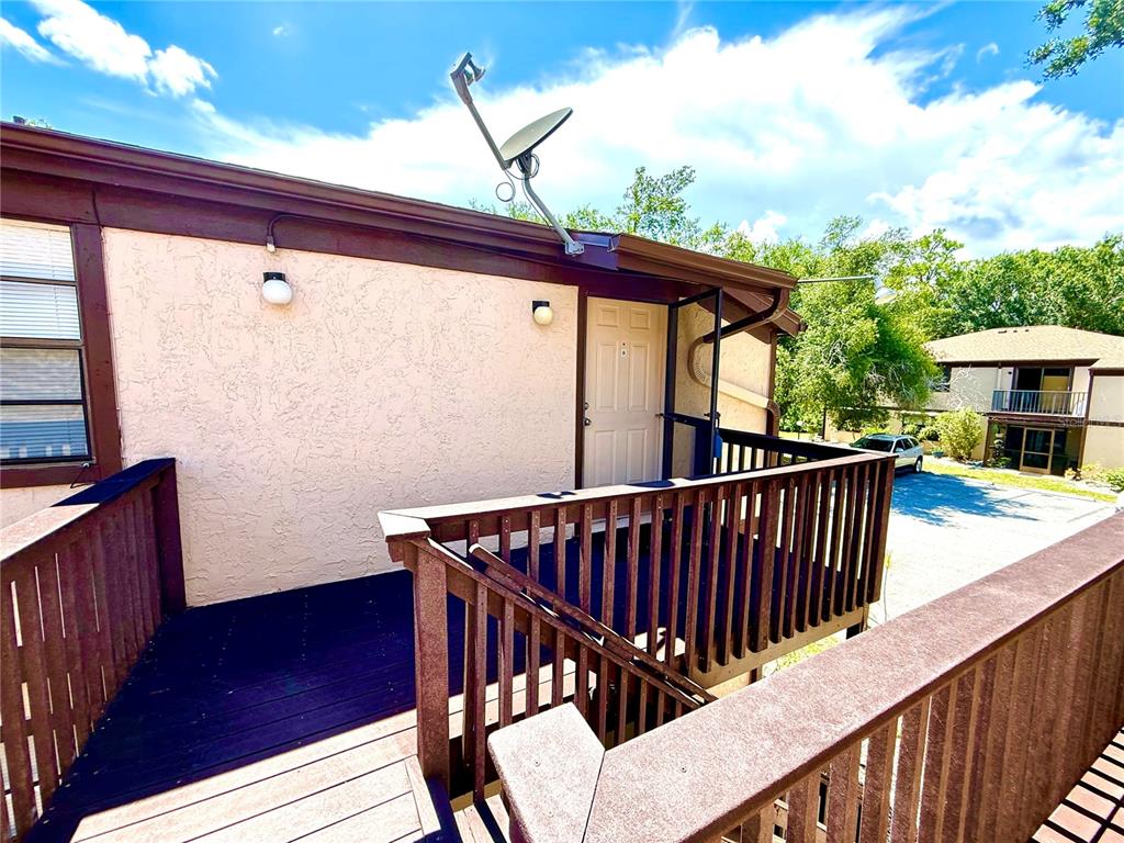 An exterior view of a second-story wooden deck with a door and satellite dish — 4022 BEAVER LANE UNIT 1000H, PORT CHARLOTTE, FL