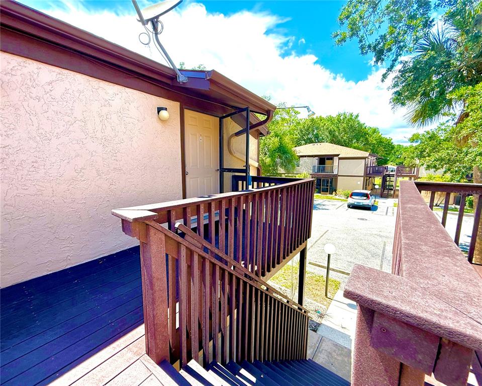 An exterior view of a wooden staircase leading to an upper-level apartment entrance — 4022 BEAVER LANE UNIT 1000H, PORT CHARLOTTE, FL