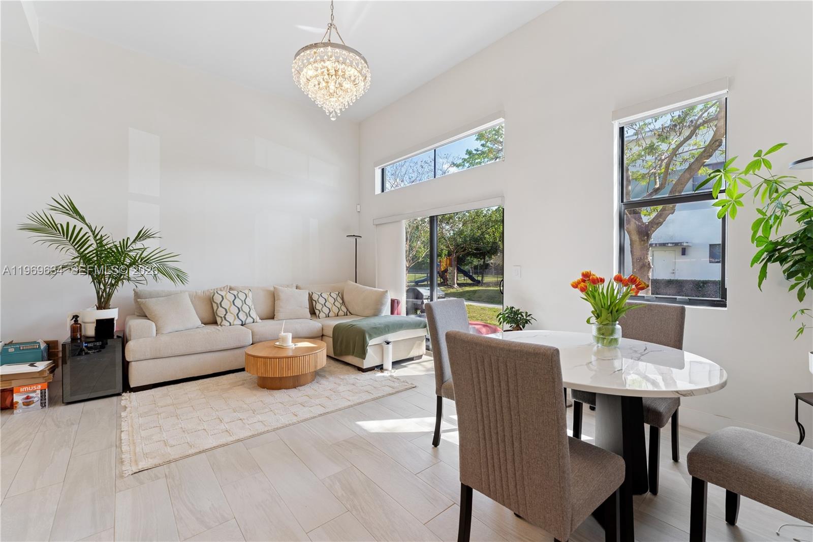 A bright living and dining area features high ceilings, a chandelier, and large windows — 4440 NW 8th Ct, Plantation FL 33317, PLANTATION, FL