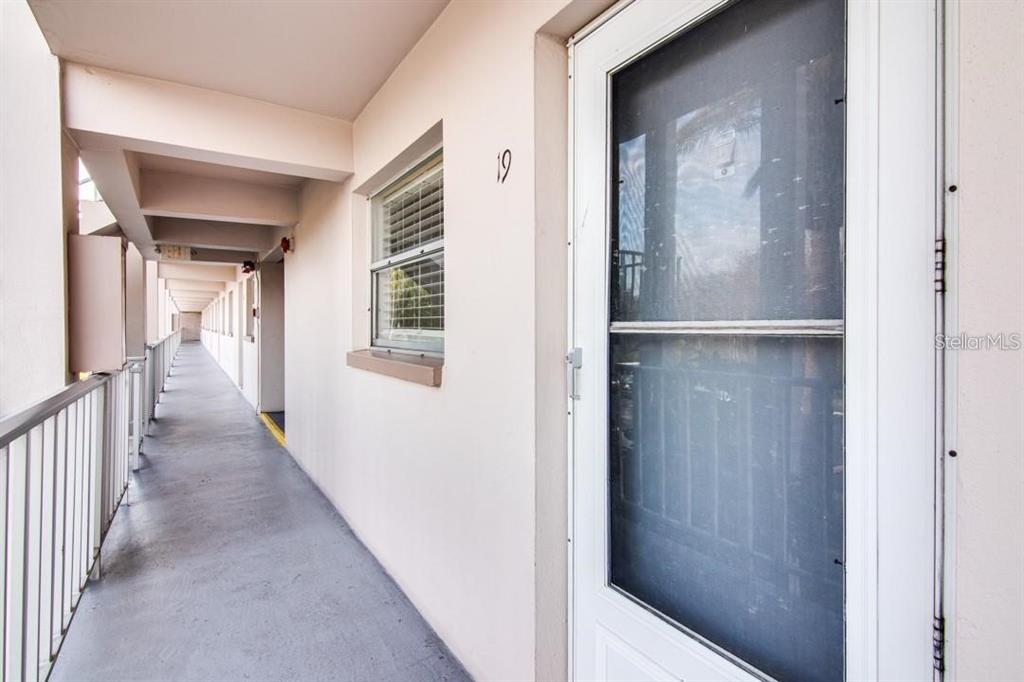 An exterior view of an apartment building hallway with a screen door marked number 19 — 1303 S HERCULES AVENUE UNIT 19, CLEARWATER, FL