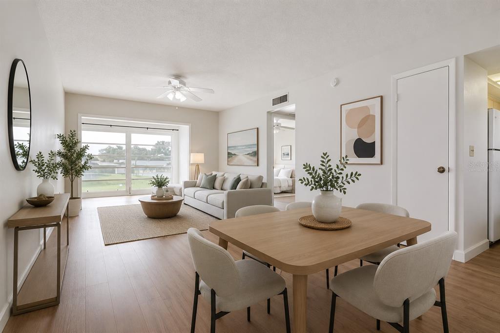 A bright living and dining area with light wood flooring, neutral furniture, and large windows — 1303 S HERCULES AVENUE UNIT 19, CLEARWATER, FL