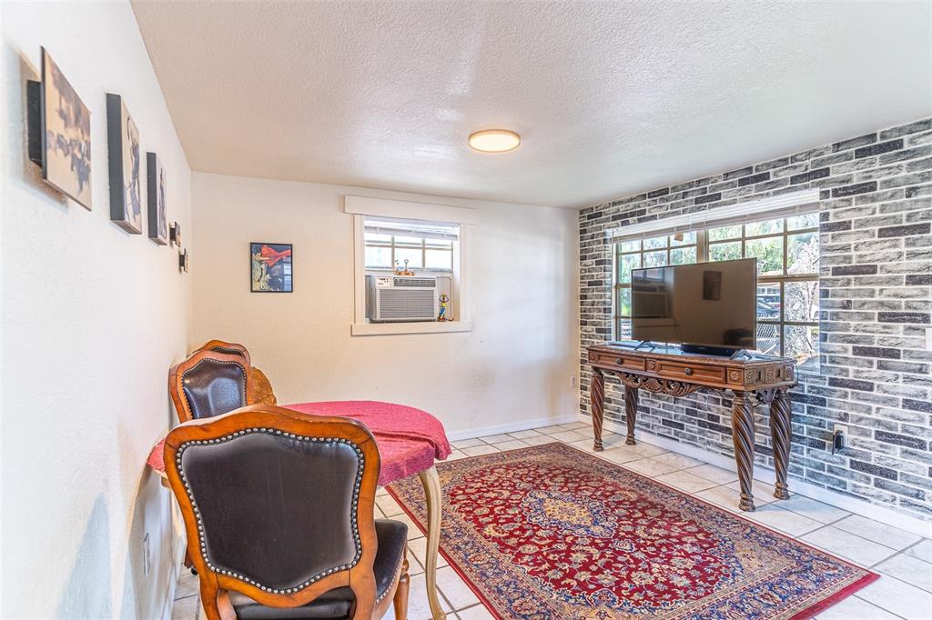 A room features a dining table, a television on a console, and a brick-patterned wall — 225 W NORTHSIDE DRIVE, LAKE WALES, FL