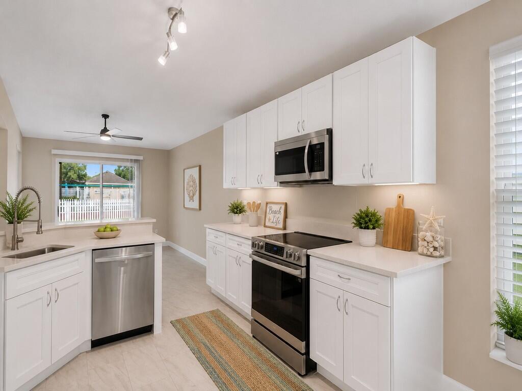 A kitchen features white cabinets, stainless steel appliances, light countertops, and a neutral color palette — 962 E 13th Square, Vero Beach FL 32960, VERO BEACH, FL