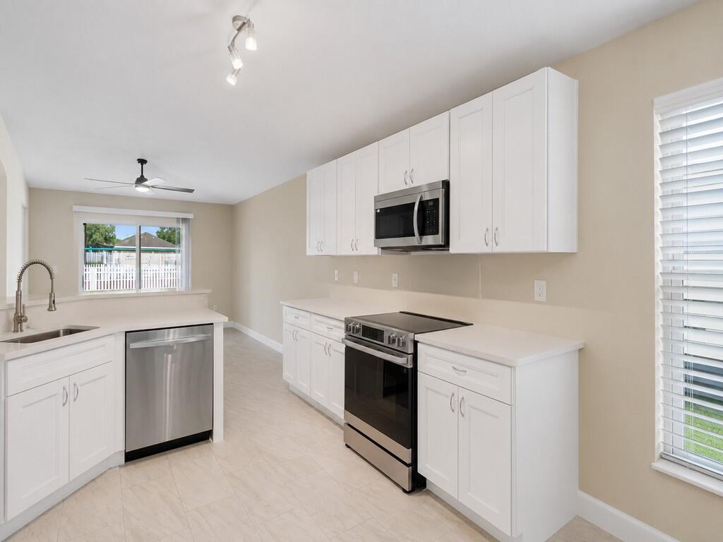 A kitchen with white cabinets, stainless steel appliances, and light-colored tile flooring — 962 E 13th Square, Vero Beach FL 32960, VERO BEACH, FL