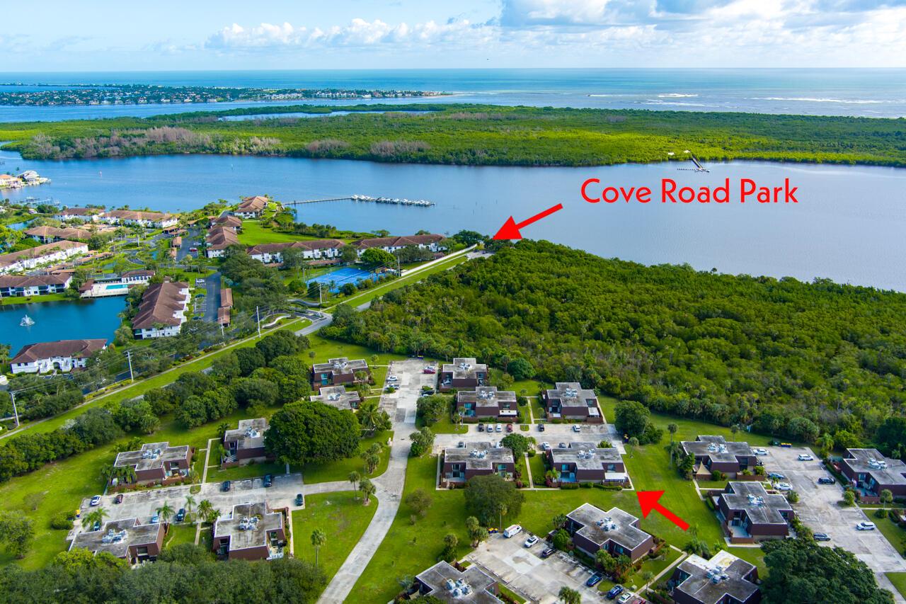 An aerial view shows residential buildings, lush green vegetation, and a nearby waterfront park — 6197 SE Riverboat Drive # 1008, Stuart FL 34997, STUART, FL