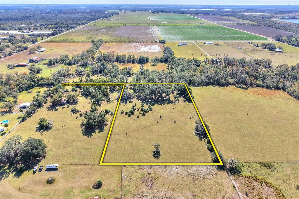 An aerial view shows a large, fenced-in grassy lot surrounded by trees and rural fields — 0 CARLTON LAKE ROAD, WIMAUMA, FL