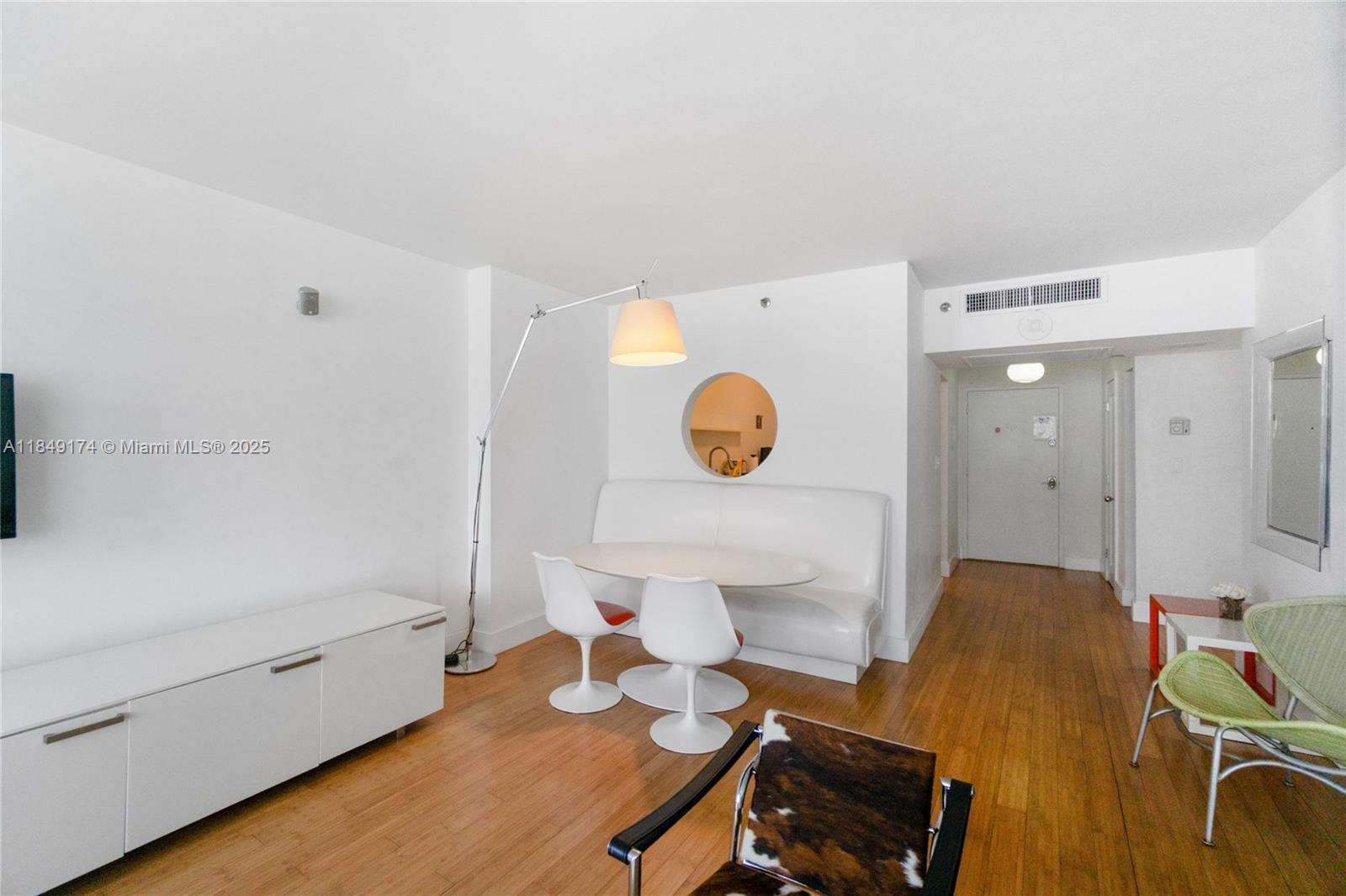A dining area with a white banquette and two chairs sits on hardwood flooring — 100 Lincoln Rd # 923, Miami Beach FL 33139, MIAMI BEACH, FL