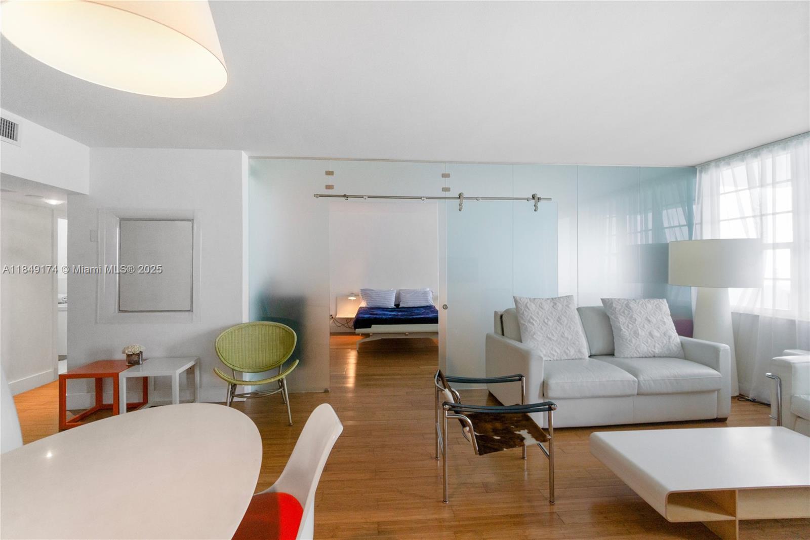 A living room with a sliding glass partition leading to a bedroom with wood floors — 100 Lincoln Rd # 923, Miami Beach FL 33139, MIAMI BEACH, FL