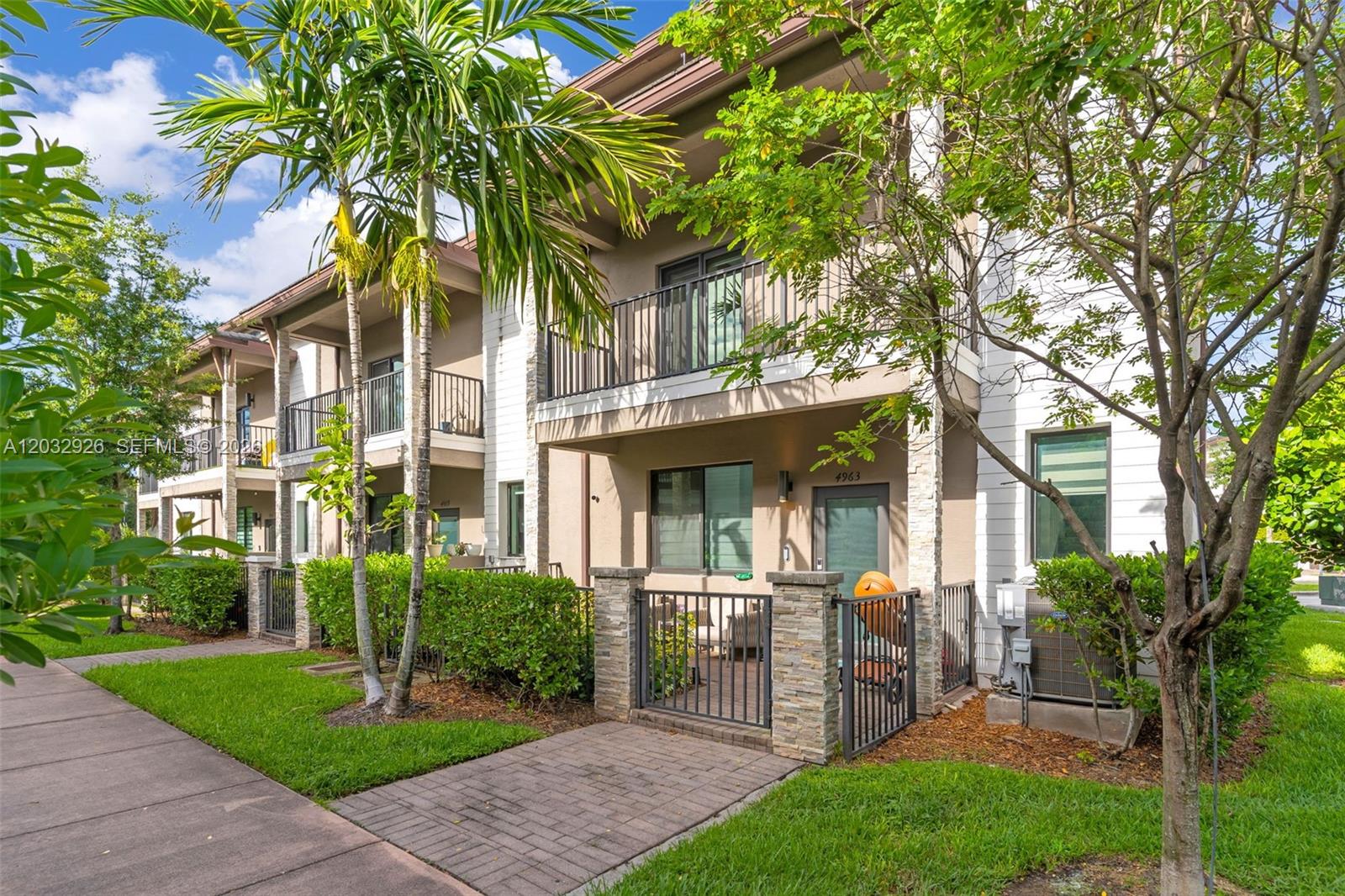 A two-story townhouse exterior features a gated front patio, stone accents, and a balcony — 4963 NW 83rd Path # 4963, Doral FL 33166, DORAL, FL