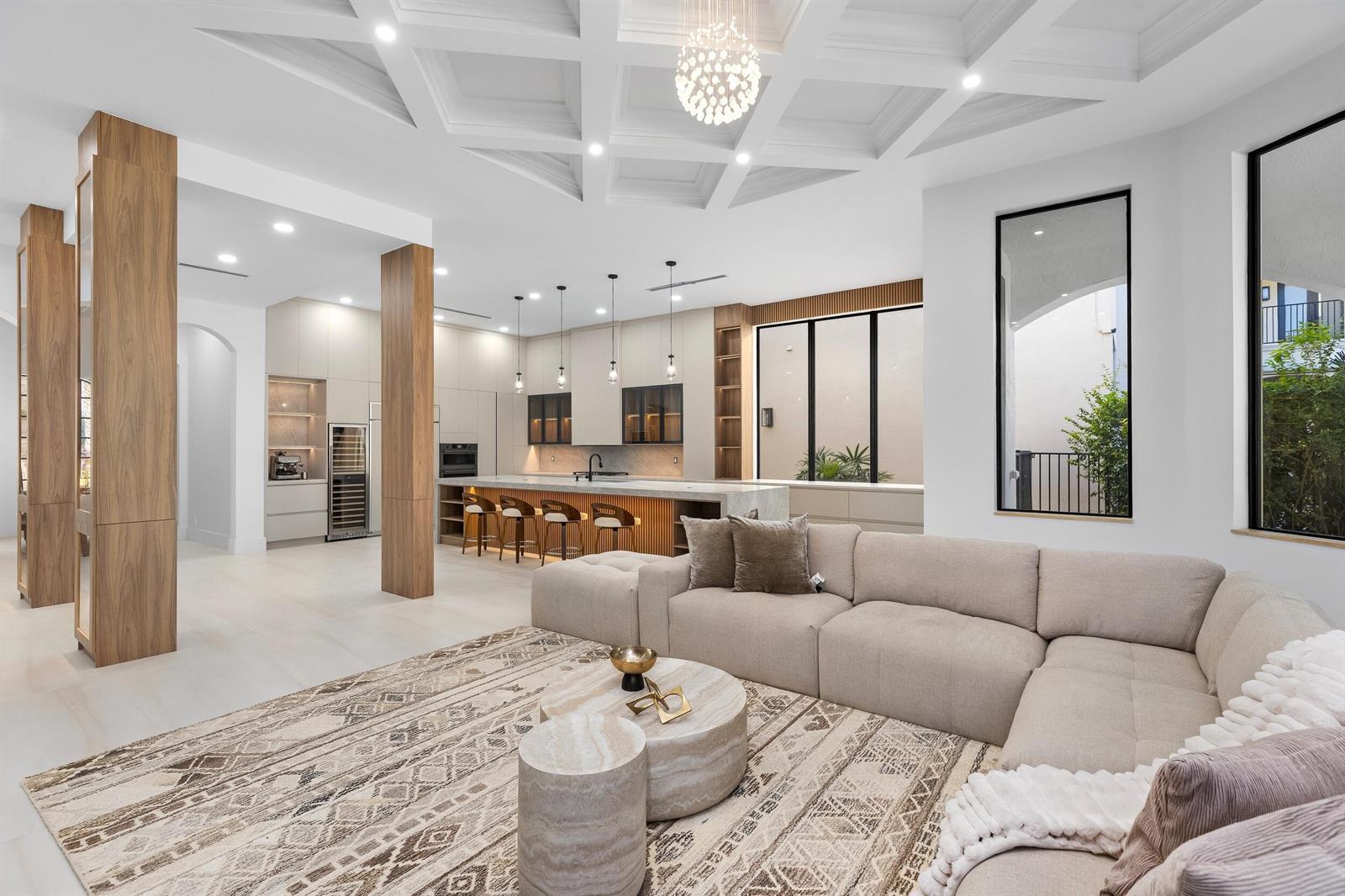 A modern open-concept living room and kitchen featuring a coffered ceiling and wood columns — 17606 Circle Pond Court, Boca Raton FL 33496, BOCA RATON, FL