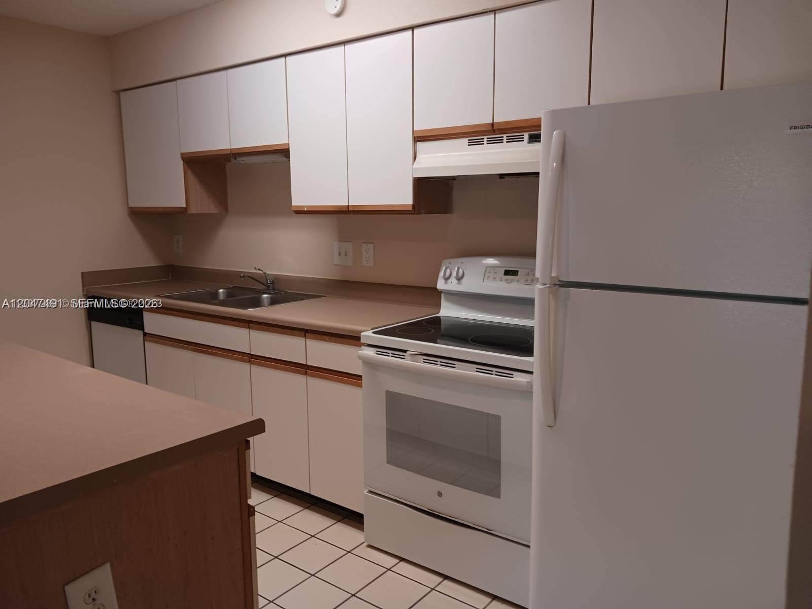 A kitchen features white cabinets, a white stove, a white refrigerator, and tan countertops — POMPANO BEACH, FL