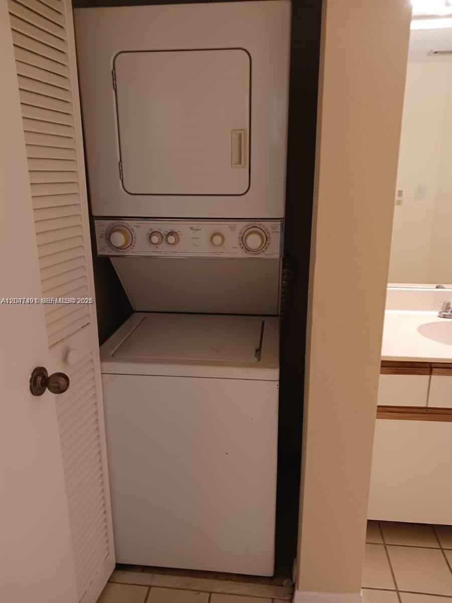 A stacked washer and dryer unit is located in a closet next to a bathroom — POMPANO BEACH, FL