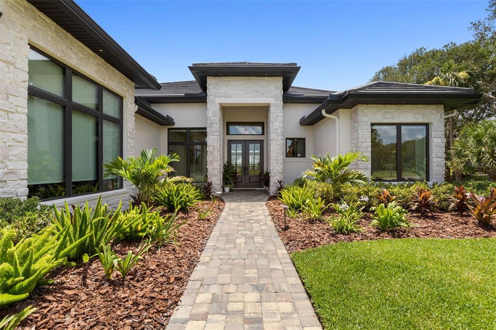 A stone-accented modern house exterior features a paved walkway leading to a double front door — 118 SEASIDE LANDINGS DRIVE N, FLAGLER BEACH, FL