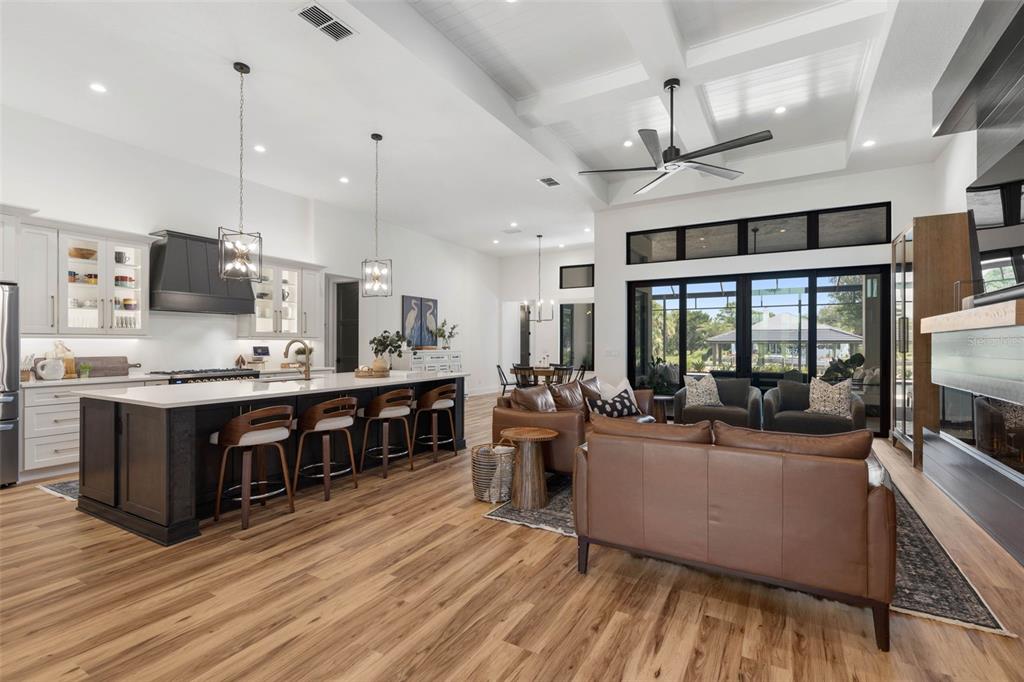 An open-concept kitchen and living area features a large island, leather furniture, and vaulted ceilings — 118 SEASIDE LANDINGS DRIVE N, FLAGLER BEACH, FL
