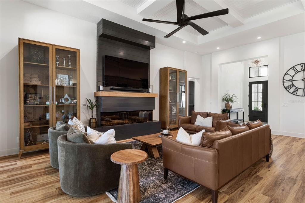 A living room features a dark fireplace, wood cabinets, leather sofas, and a ceiling fan — 118 SEASIDE LANDINGS DRIVE N, FLAGLER BEACH, FL