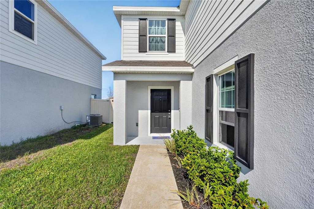 A concrete walkway leads to the front entrance of a two-story house with gray siding — 5007 STARBOARD STREET, HAINES CITY, FL