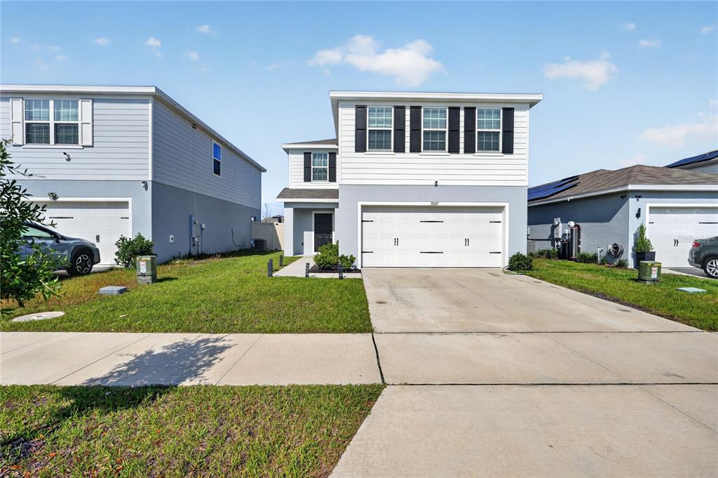 A two-story suburban house with a white exterior, a two-car garage, and a concrete driveway — 5007 STARBOARD STREET, HAINES CITY, FL