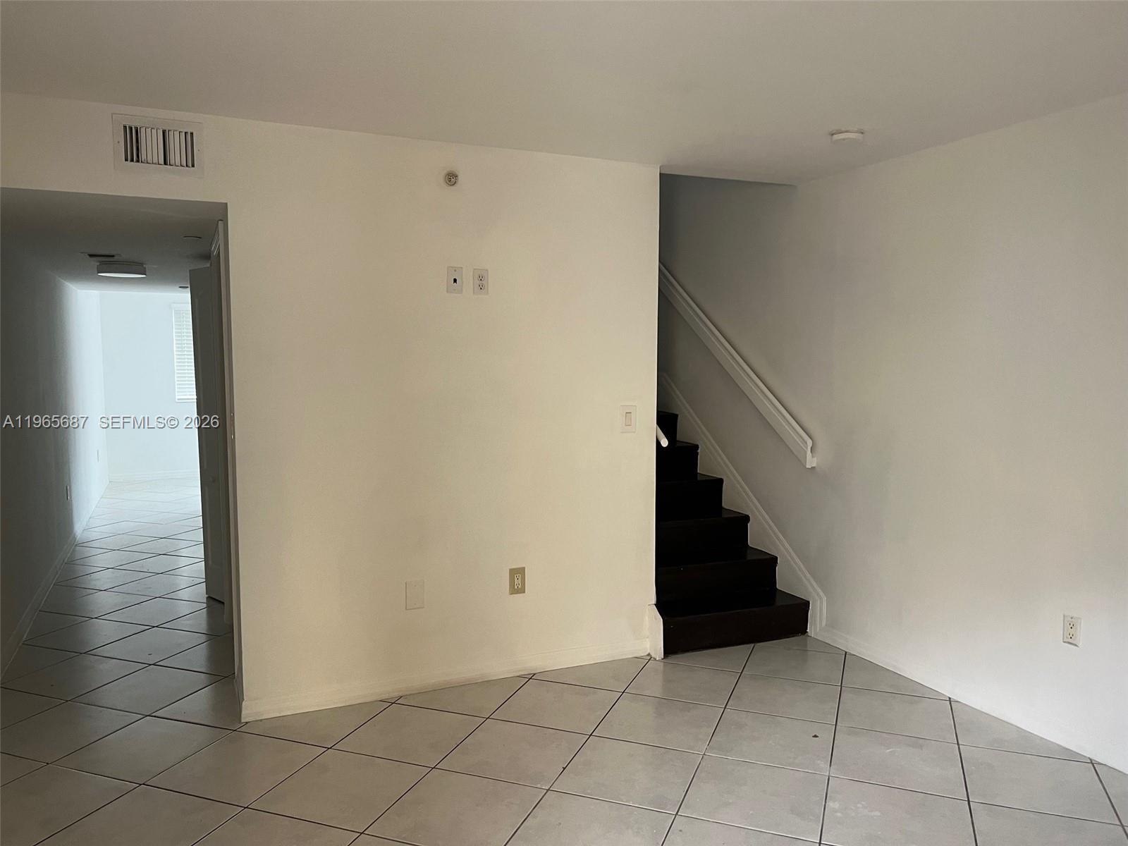 A room with light-colored tile flooring, a staircase with dark steps, and a doorway — 12645 SW 91st St # 202, Miami FL 33186, MIAMI, FL