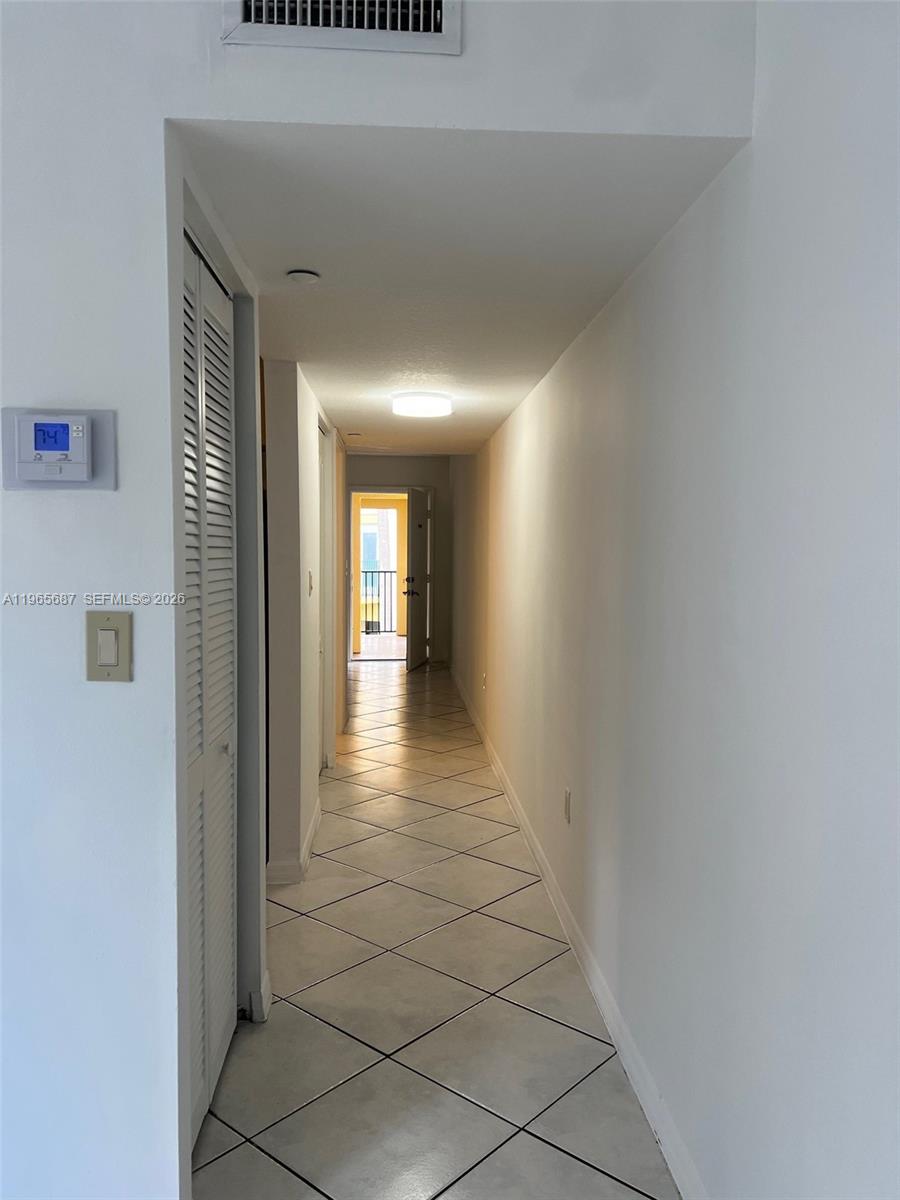 A narrow hallway with white walls and diagonal tile flooring leads to an open doorway — 12645 SW 91st St # 202, Miami FL 33186, MIAMI, FL