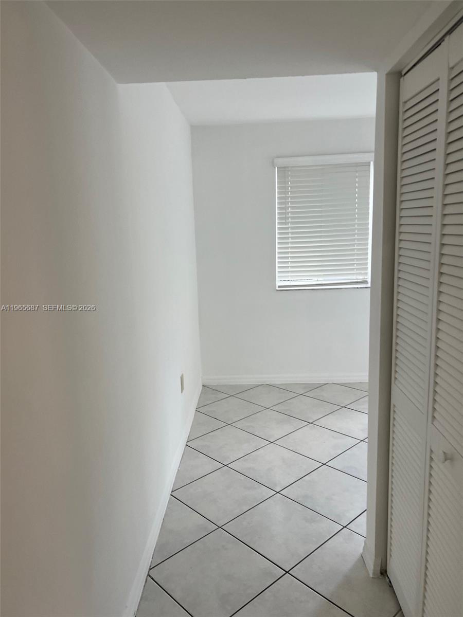 A small, white-walled room features gray tile flooring and a window with white blinds — 12645 SW 91st St # 202, Miami FL 33186, MIAMI, FL