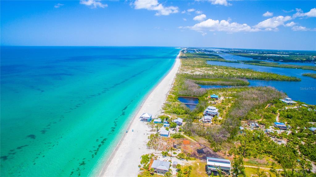 An aerial view shows a sandy beach along turquoise water next to coastal homes — 13 SEAWARD CIRCLE, PLACIDA, FL