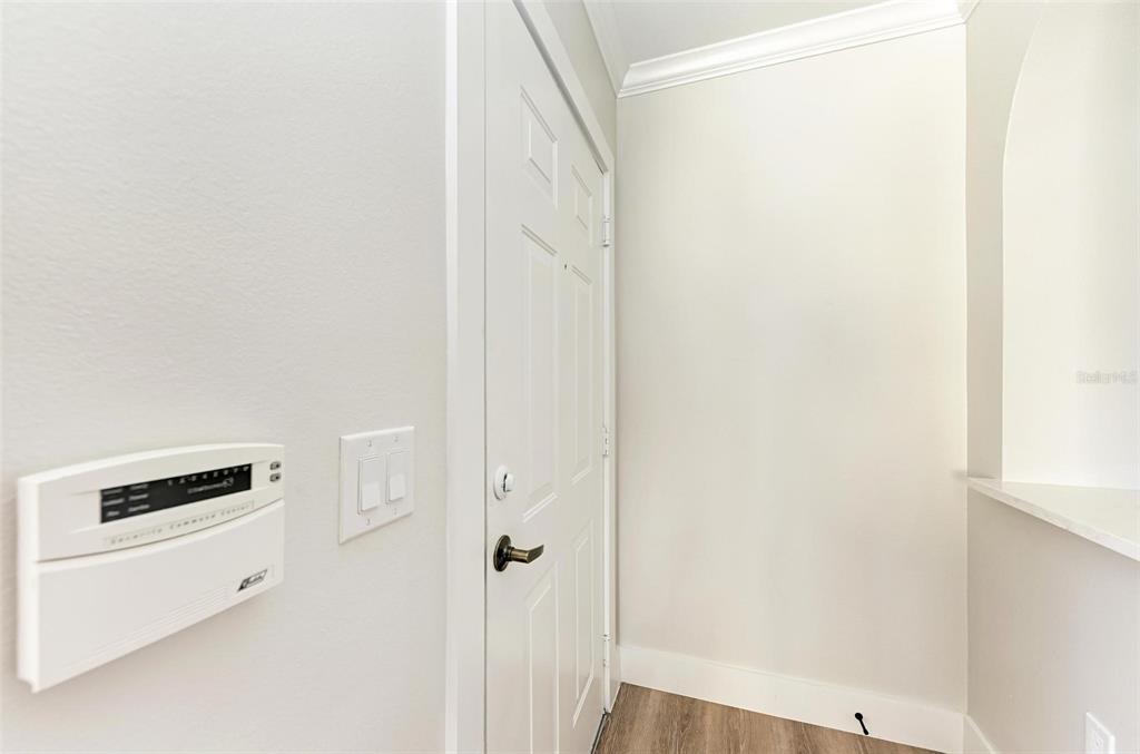 A white door with a security panel and light switches on the adjacent wall — 3005 CHIANTI COURT UNIT 1003, SARASOTA, FL