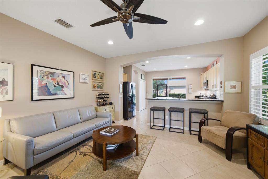 A living room with a grey sofa, coffee table, and an open kitchen with bar seating — 5002 BOSTON COMMON GLEN, BRADENTON, FL