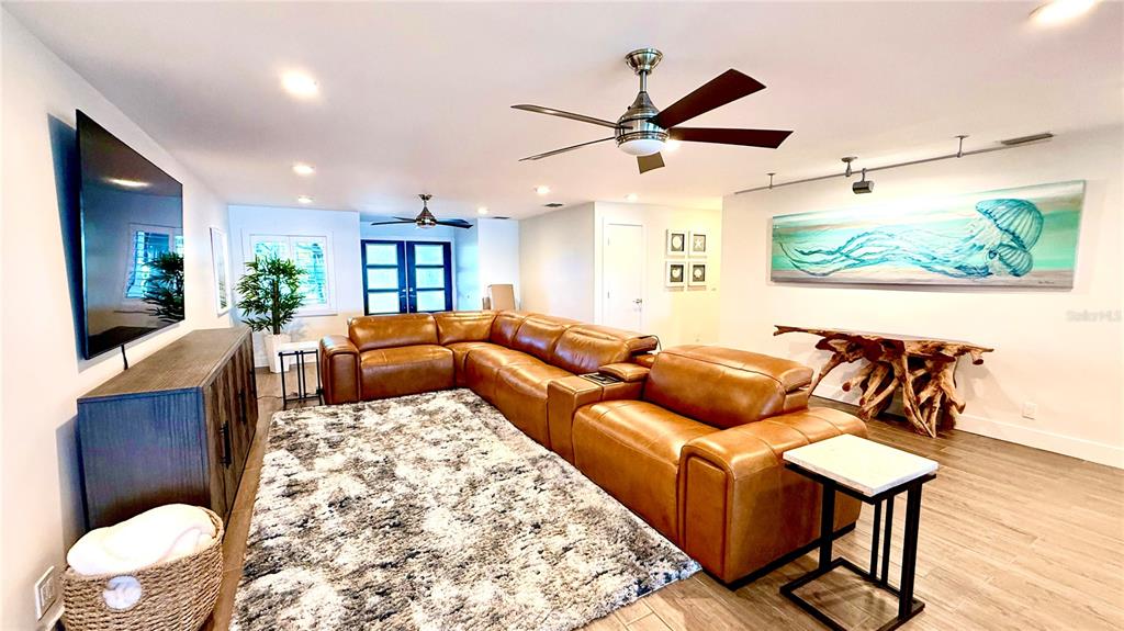 A living room features a brown leather sectional, a textured rug, and a jellyfish painting — 980 BOCA CIEGA ISLE DRIVE, ST PETE BEACH, FL