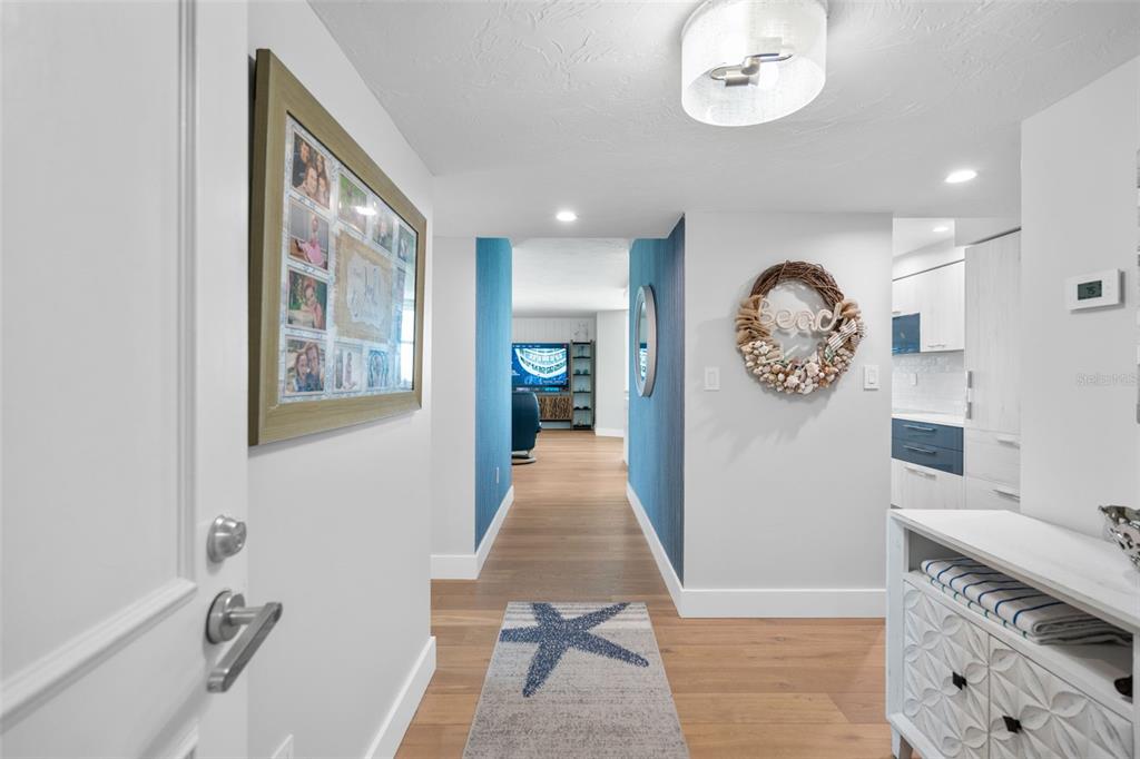 A hallway with light wood floors, a starfish rug, and a blue accent wall — 1050 LONGBOAT CLUB ROAD UNIT 901, LONGBOAT KEY, FL