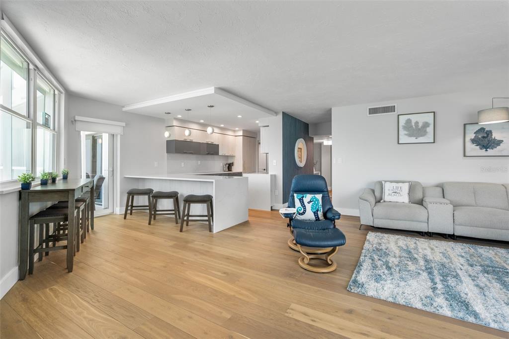 An open-concept living room and kitchen featuring light wood floors and a breakfast bar — 1050 LONGBOAT CLUB ROAD UNIT 901, LONGBOAT KEY, FL