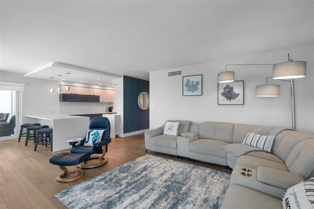 A living room with a sectional sofa, a blue recliner, and an open kitchen area — 1050 LONGBOAT CLUB ROAD UNIT 901, LONGBOAT KEY, FL