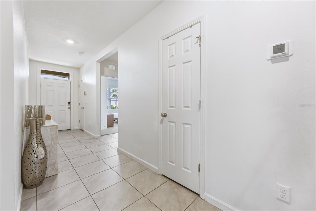 A tiled entryway features a white door, a closet, and a wall-mounted thermostat — 7339 TOURMALINE DRIVE, GRANT VALKARIA, FL