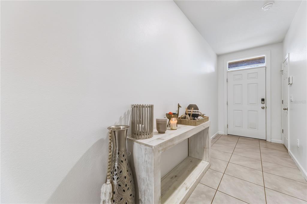 An entryway features a white console table, decorative accents, and tile flooring near a front door — 7339 TOURMALINE DRIVE, GRANT VALKARIA, FL