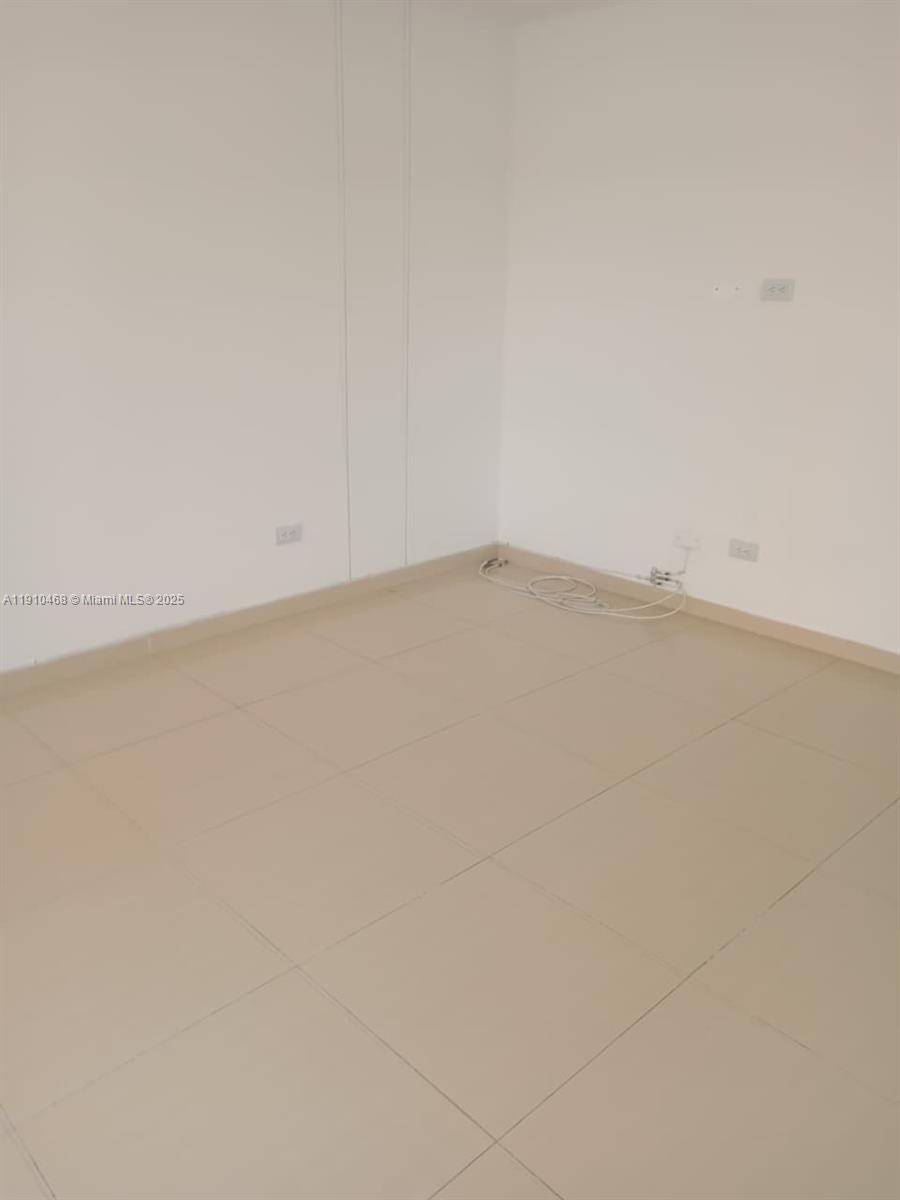 An empty room features plain white walls and light-colored square floor tiles — Calle 2 Oeste #24A174 Miraflor # 101, 00000, FL