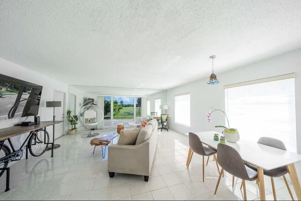 A bright living and dining area with white tile floors, a sofa, and large windows — 6 Lucerne Avenue # 3, FL 33460, FL