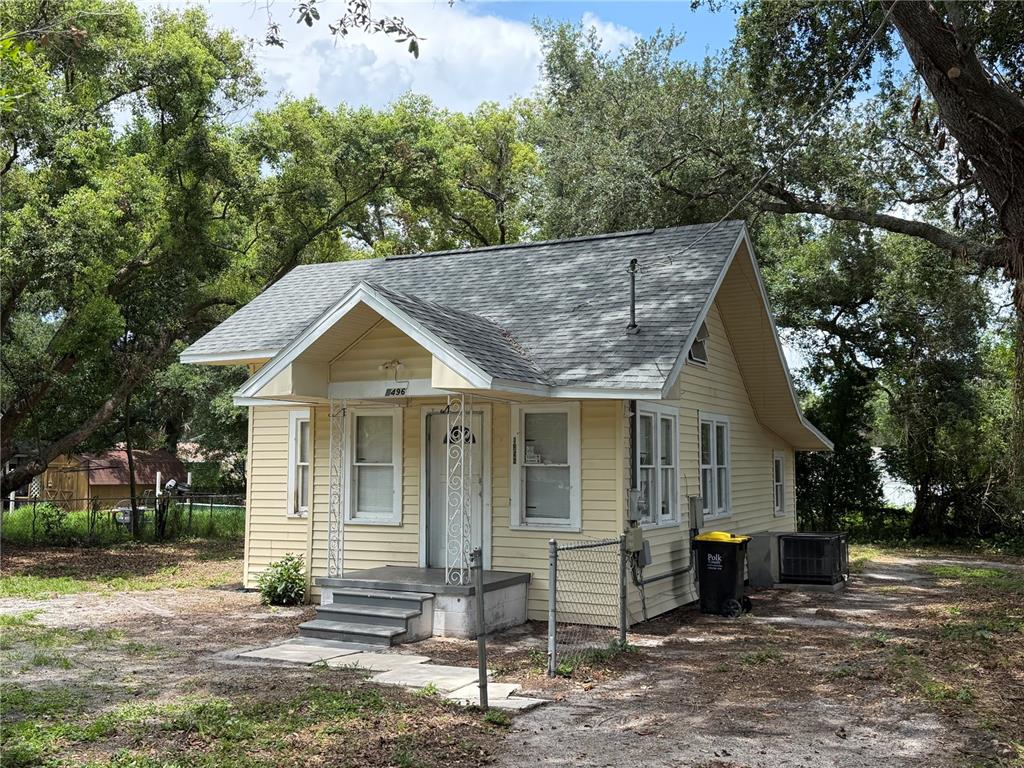 A small, yellow, single-story house with a gabled roof and a front porch — 1496 33RD STREET NW, WINTER HAVEN, FL