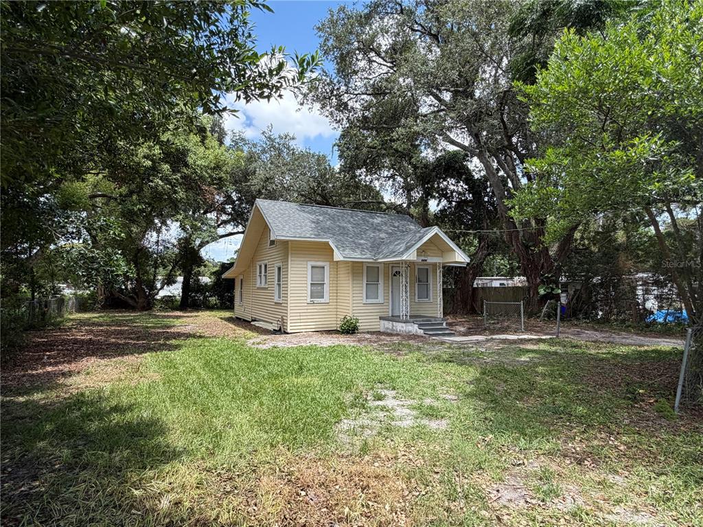 A small, yellow, single-story house with a gabled roof sits on a grassy lot — 1496 33RD STREET NW, WINTER HAVEN, FL