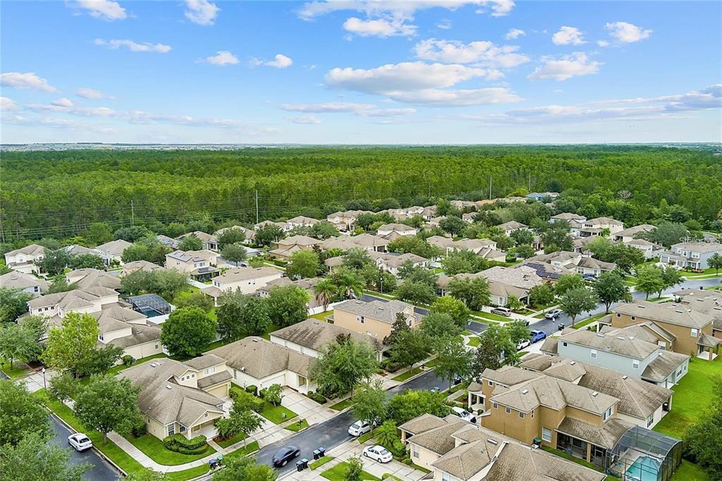 An aerial view shows a suburban neighborhood with houses, streets, and a large forest background — 8556 GREENBANK BOULEVARD, WINDERMERE, FL