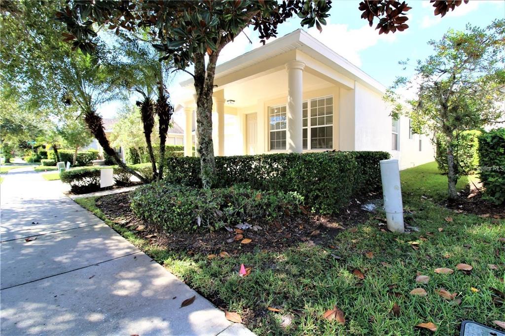 A single-story house with a covered front porch and columns behind a manicured hedge — 8556 GREENBANK BOULEVARD, WINDERMERE, FL