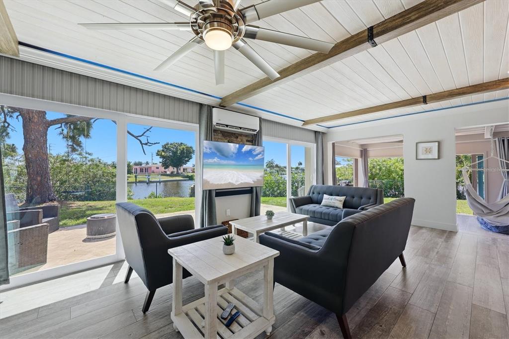 A living room features dark furniture, a ceiling fan, and large windows overlooking a canal — 108 BUCKEYE AVENUE NW, PORT CHARLOTTE, FL