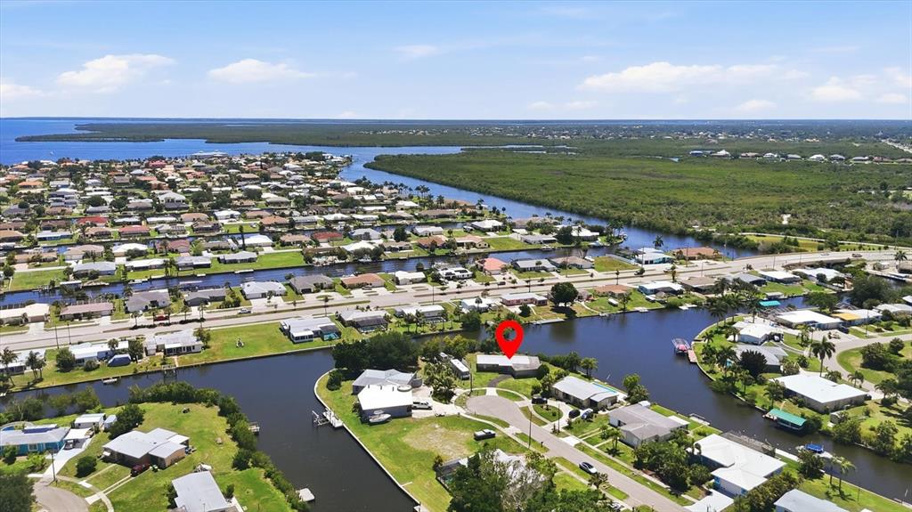 An aerial view shows a residential neighborhood with houses situated along a network of canals — 108 BUCKEYE AVENUE NW, PORT CHARLOTTE, FL
