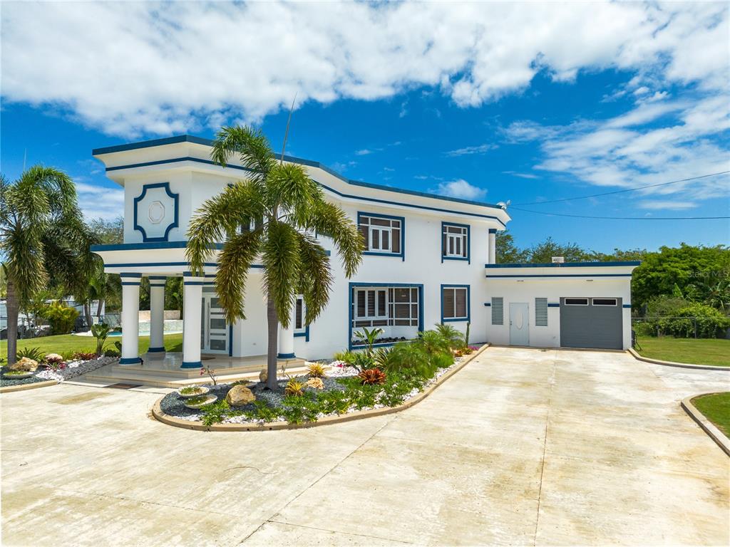 A two-story white house with blue trim features a palm tree and a concrete driveway — 1 CALLE ISAMAR, ISABELA, PR