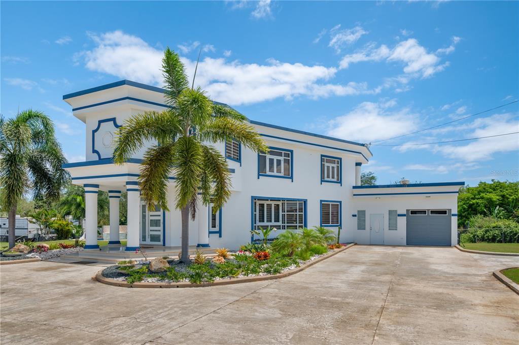A two-story white house with blue trim, a palm tree, and a concrete driveway — 1 CALLE ISAMAR, ISABELA, PR