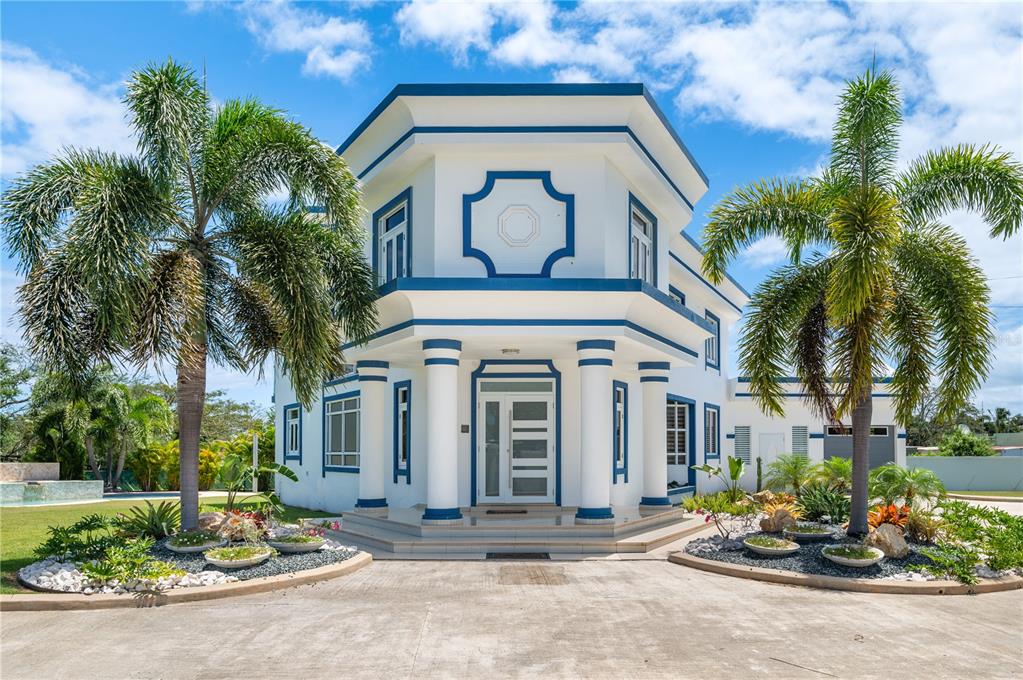 A two-story white house with blue trim, columns, and palm trees in the front yard — 1 CALLE ISAMAR, ISABELA, PR