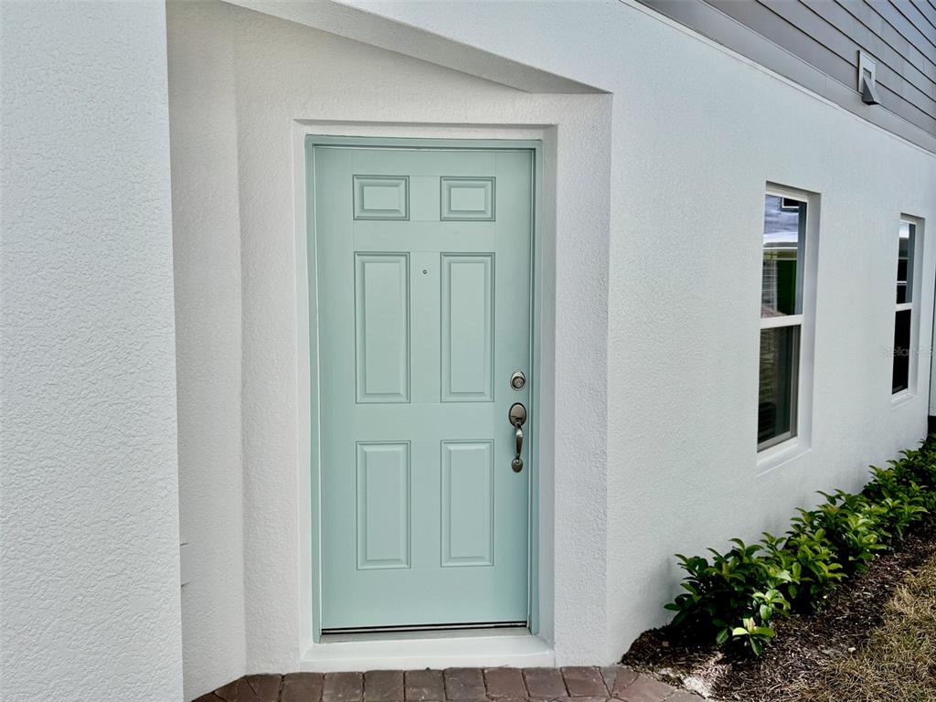 A light green front door is set into a white stucco exterior wall — 5094 RAIN SHADOW DRIVE, ST CLOUD, FL