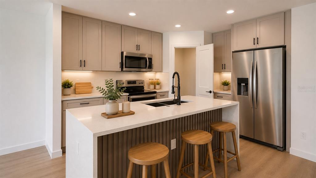 A modern kitchen features light wood cabinets, stainless steel appliances, and a slatted kitchen island — 644 and 646 E FRANKLIN STREET, OVIEDO, FL