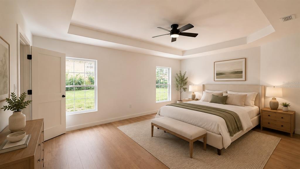 A bedroom features a tray ceiling, a ceiling fan, light wood flooring, and a bed — 644 and 646 E FRANKLIN STREET, OVIEDO, FL