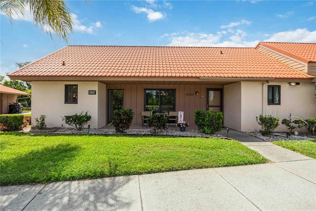 A single-story house with a terracotta tile roof and a front patio — 6567 DRAW LANE UNIT 104, SARASOTA, FL