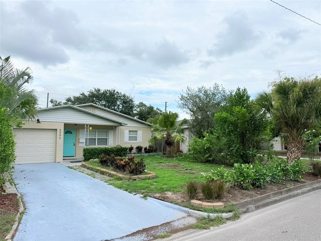 A single-story house with a blue front door, a painted driveway, and a front lawn — 5545 3RD AVE N, ST PETERSBURG, FL