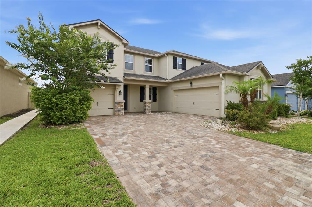 A two-story suburban house with a paver driveway, two-car garage, and a landscaped front yard — 1011 LEE SHORE STREET, VALRICO, FL